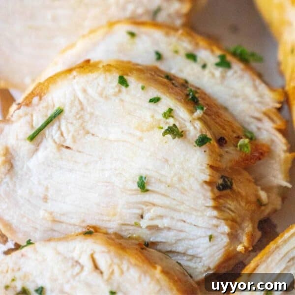 Crispy Honey Mustard Baked Chicken Drumsticks Recipe 14 Close-up of sliced, cooked chicken breast garnished with chopped herbs. The chicken, marinated in a succulent greek grilled chicken marinade, is lightly seared and appears tender and moist.