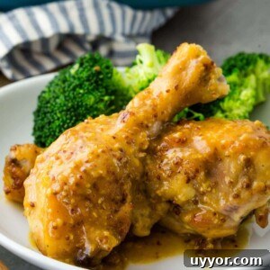 Crispy Honey Mustard Baked Chicken Drumsticks Recipe 19 Chicken thighs and broccoli on a white plate, coated with mustard.