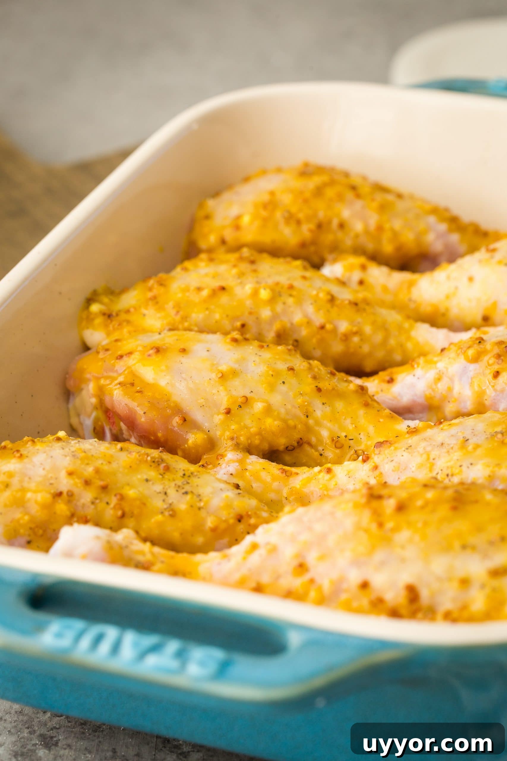Crispy Honey Mustard Baked Chicken Drumsticks Recipe 8 Honey mustard chicken drumsticks in a blue baking dish.