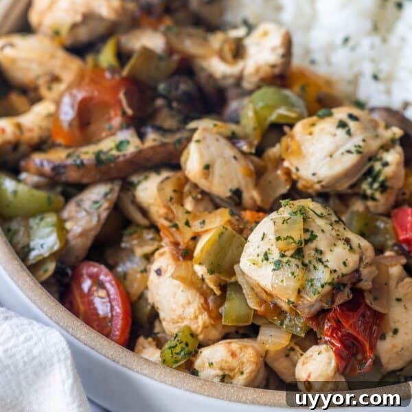 Crispy Honey Mustard Baked Chicken Drumsticks Recipe 10 A close-up of a bowl filled with cooked chicken pieces, bell peppers, tomatoes, and herbs—this Keto Italian Chicken Skillet Dinner is served with a portion of white rice visible in the background.