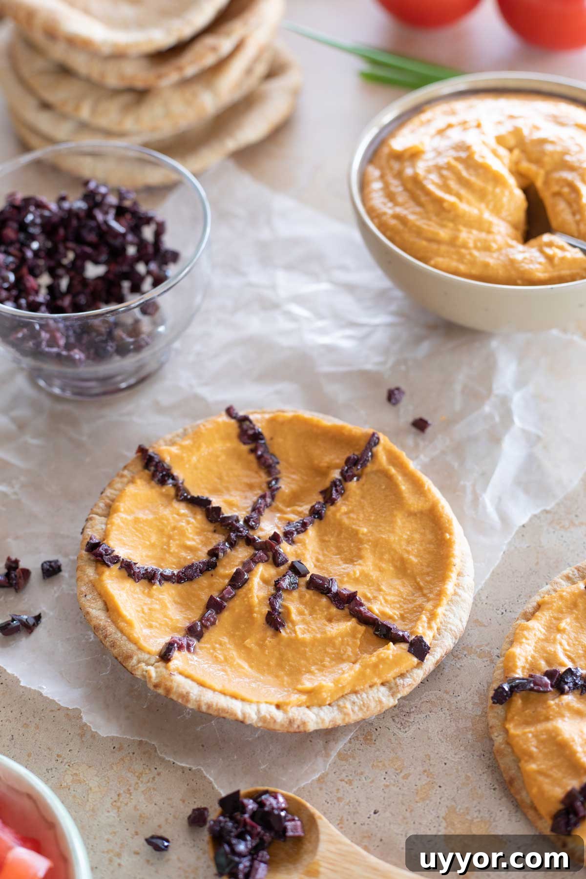 50+ Winning March Madness Game Day Recipes and Snacks 8 Closeup of one hummus-topped pita with black olives being placed to make it look like a basketball.