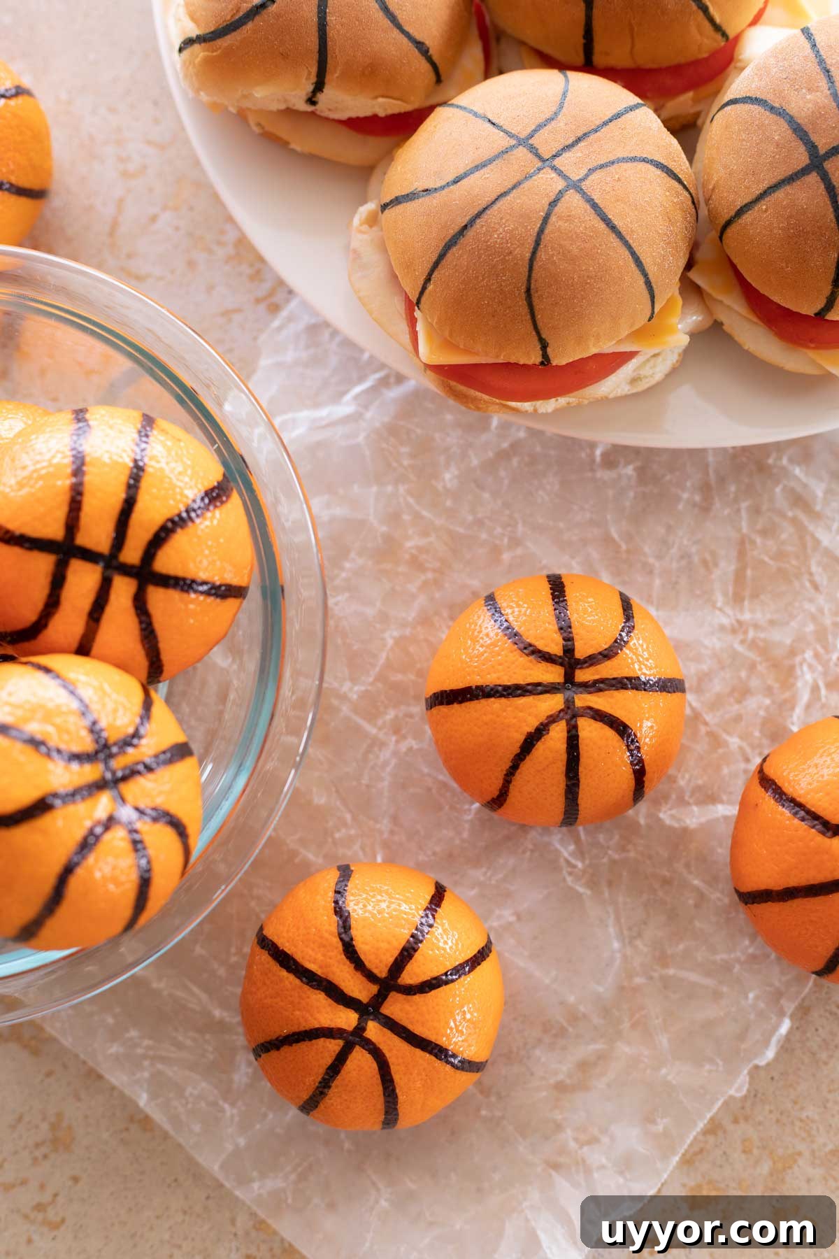 50+ Winning March Madness Game Day Recipes and Snacks 10 Overhead of several clementine basketballs with a platter of decorated sliders in background.