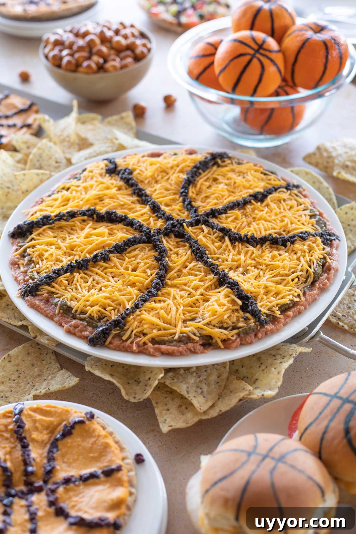 50+ Winning March Madness Game Day Recipes and Snacks 14 Layered Mexican Dip in center of other March Madness themed party foods.
