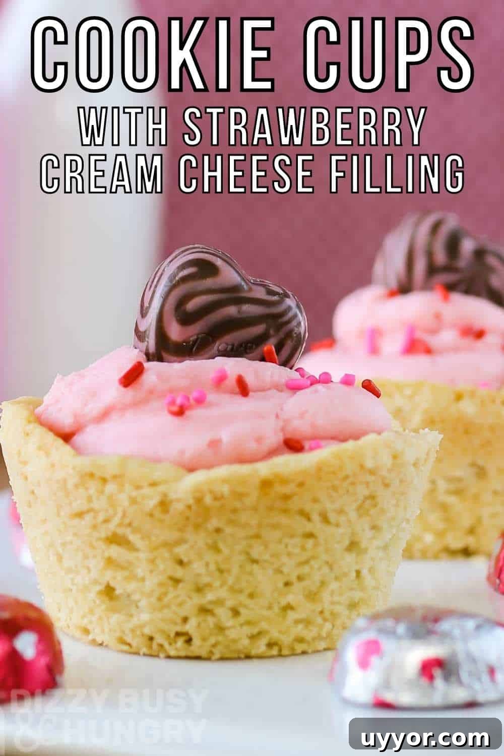 Strawberry Cream Cheese Cookie Cups: Soft Cookies Filled with Creamy Strawberry Centers 2 Side shot of two cookie cups on a white plate with chocolate hearts scattered around with a pink background.