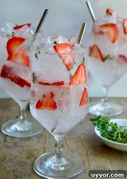 A clear glass containing sliced strawberries and crushed ice.