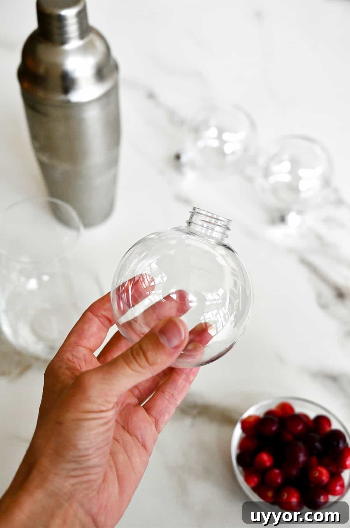 A hand holds a clear plastic Christmas ornament ball.