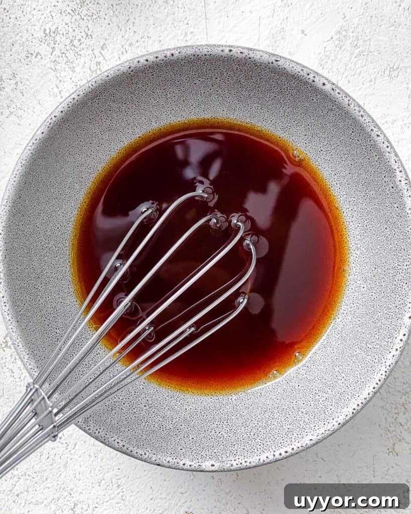 process shot of mixing sauce in a white bowl with whisk