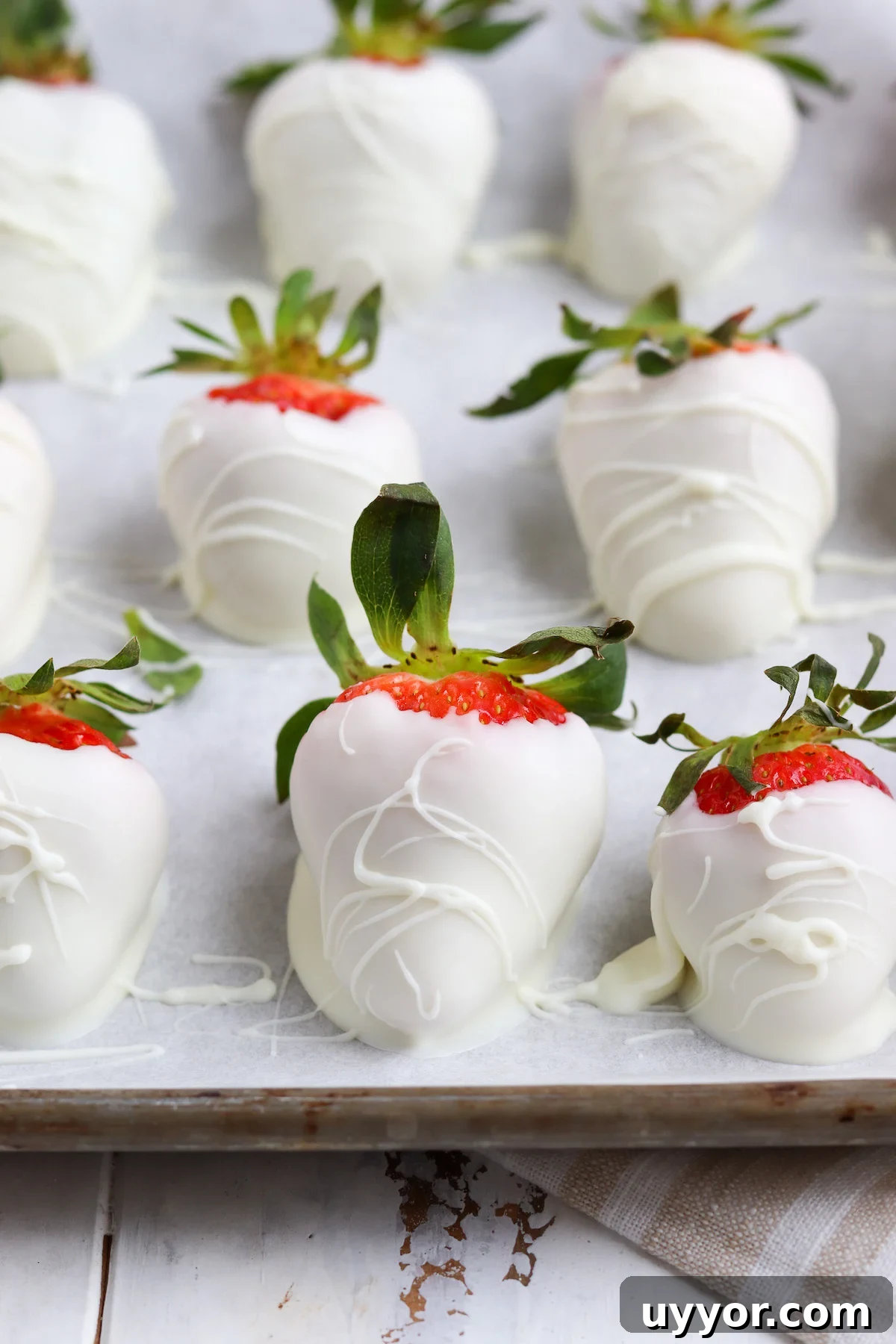 White Chocolate-Covered Strawberries: Simple Step-by-Step Recipe 3 wax paper lined baking sheet with hand-dipped white chocolate strawberries.