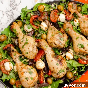 Zesty Italian Chicken Drumsticks served on a plate of salad next to a orange and white poke a dot towel