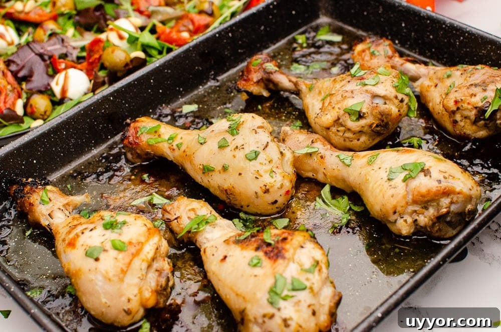 Zesty Italian Chicken Drumsticks garnished with chopped basil on a black baking tray