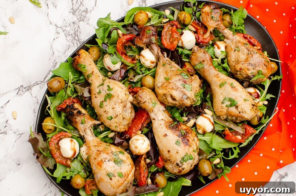 Zesty Italian Chicken Drumsticks served on a plate of salad next to a orange and white poke a dot towel