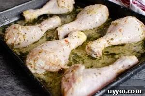 Chicken drumsticks on a black baking tray ready to cook