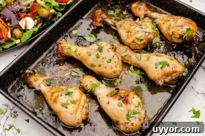 Zesty Italian Chicken Drumsticks garnished with chopped basil on a black baking tray