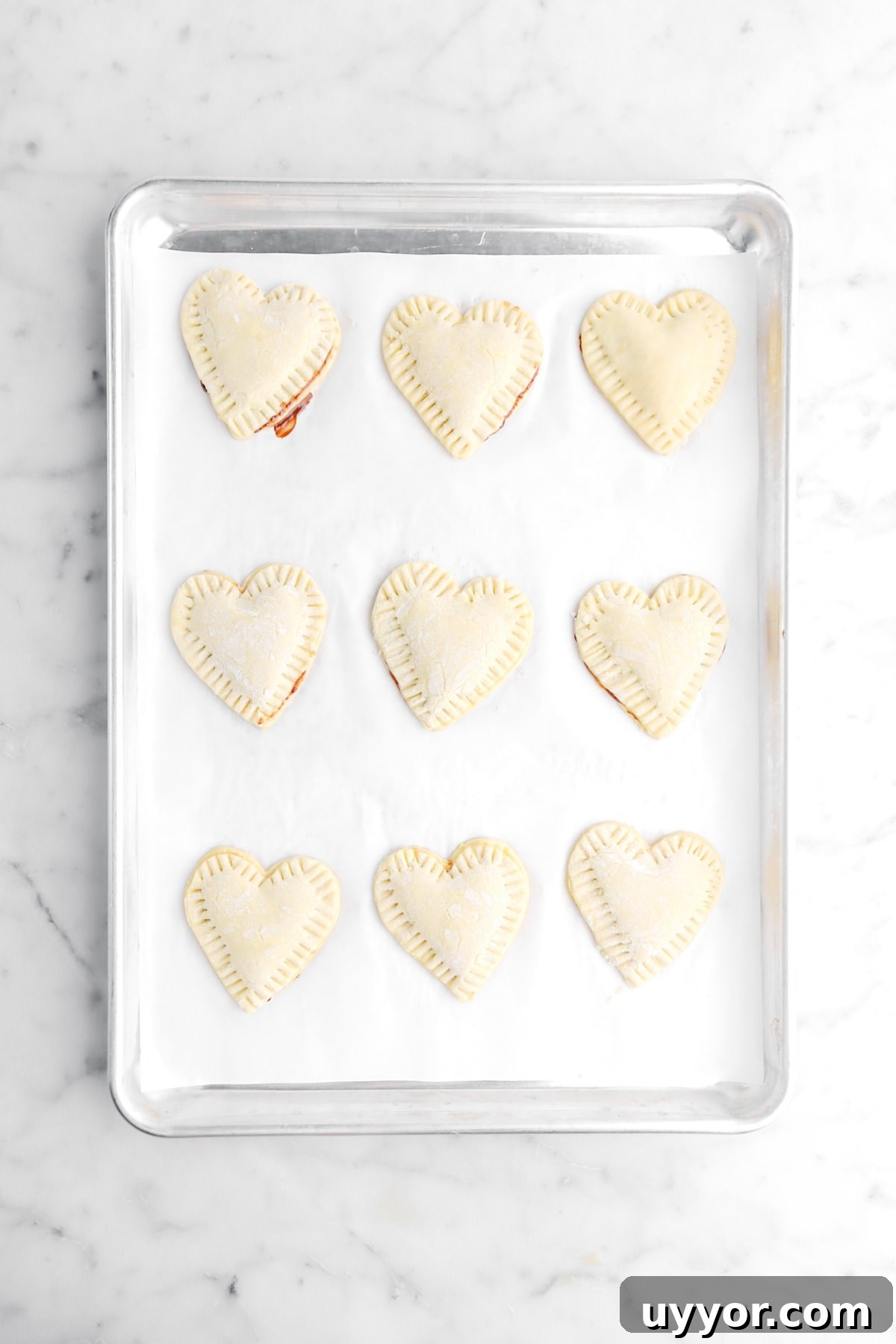 sealed heart shaped puff pastries on parchment lined sheet pan.