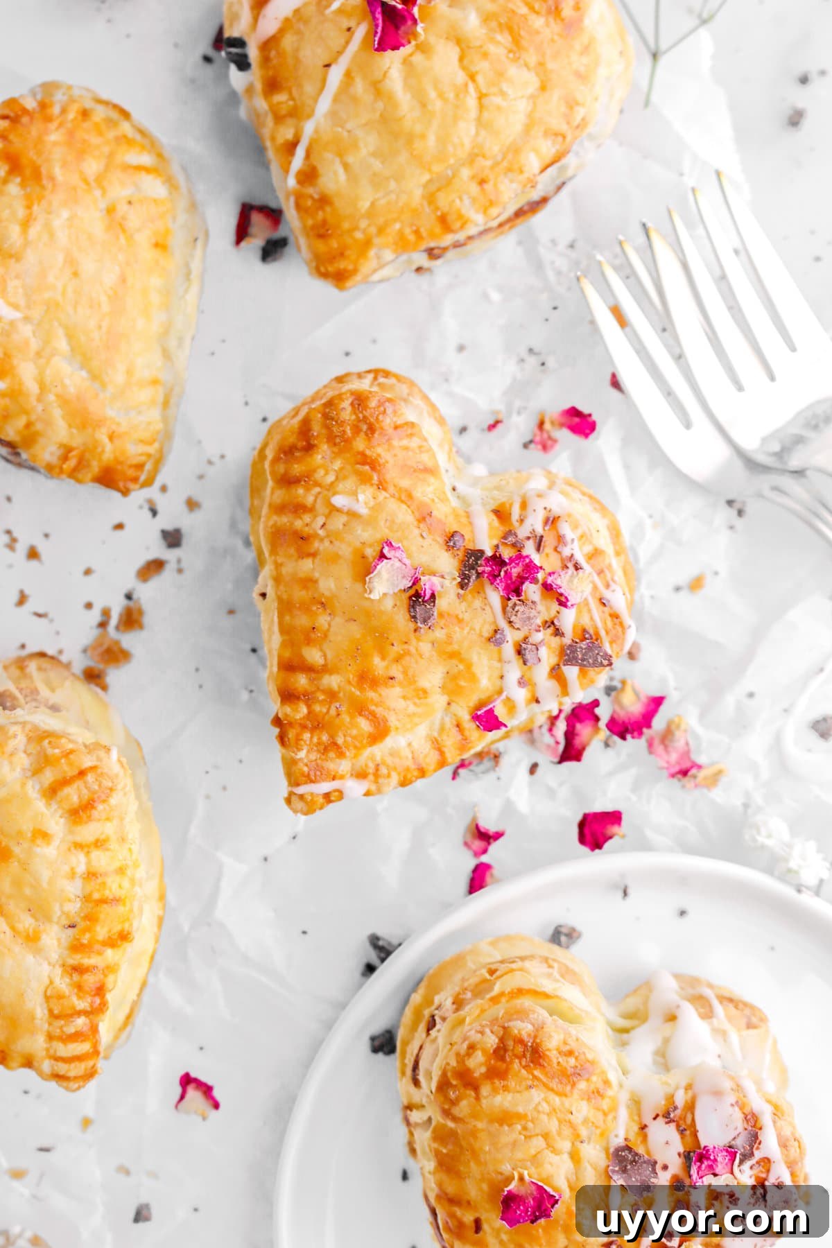 close up overhead image of heart shaped hand pie with dried rose petals and chocolate shavings on top.