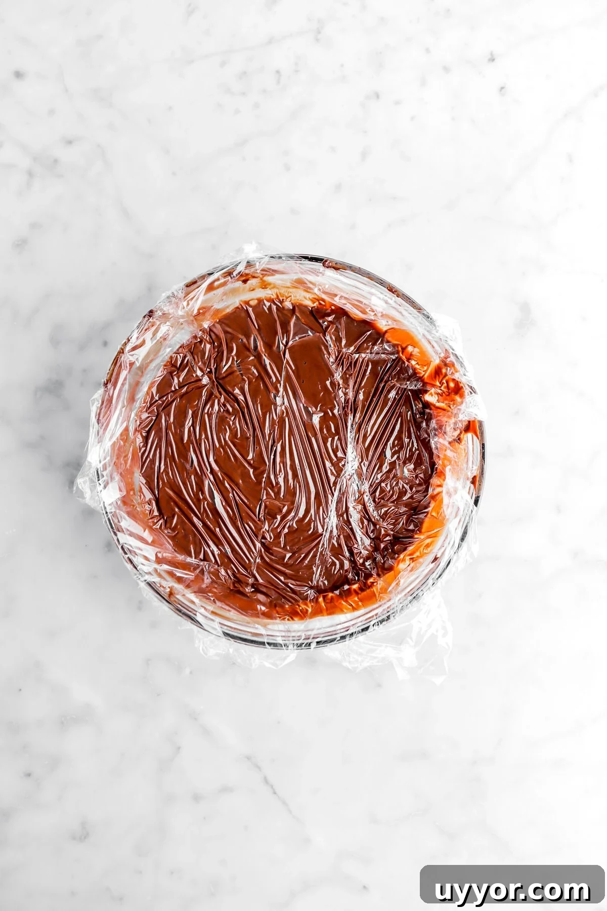 ganache covered with plastic wrap in glass bowl.