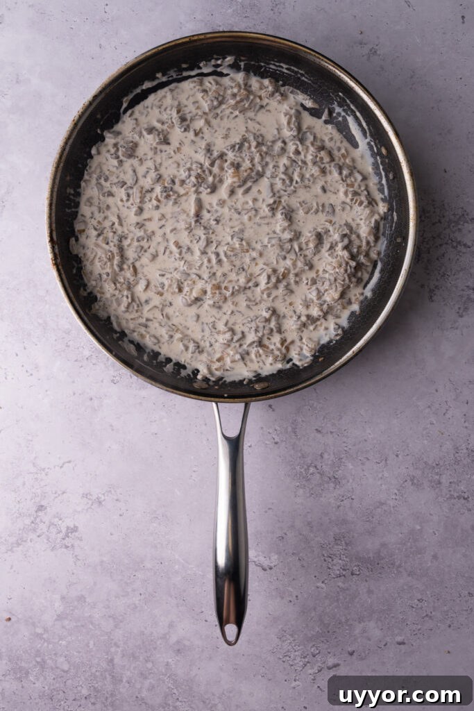 Creamy White Wine Mushroom Sauce Recipe for Pasta and Chicken 6 Cream sauce with white wine and mushrooms cooking in a saucepan.