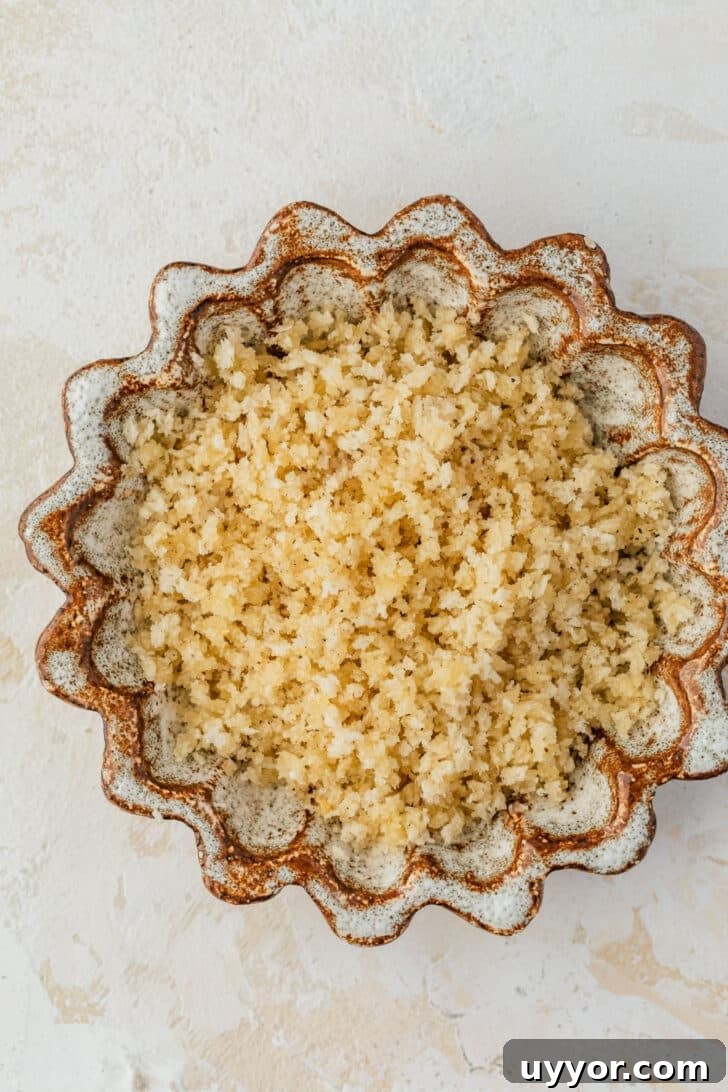 Crispy Baked Boursin Bites Without Dredging 5 A brown bowl of breadcrumbs and butter on a tan table.