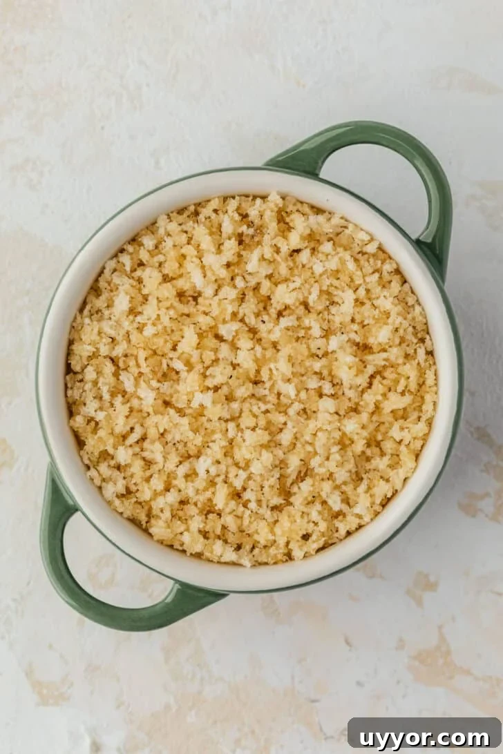 Crispy Baked Boursin Bites Without Dredging 6 A green ramekin of cheese and bread crumbs on a tan table.