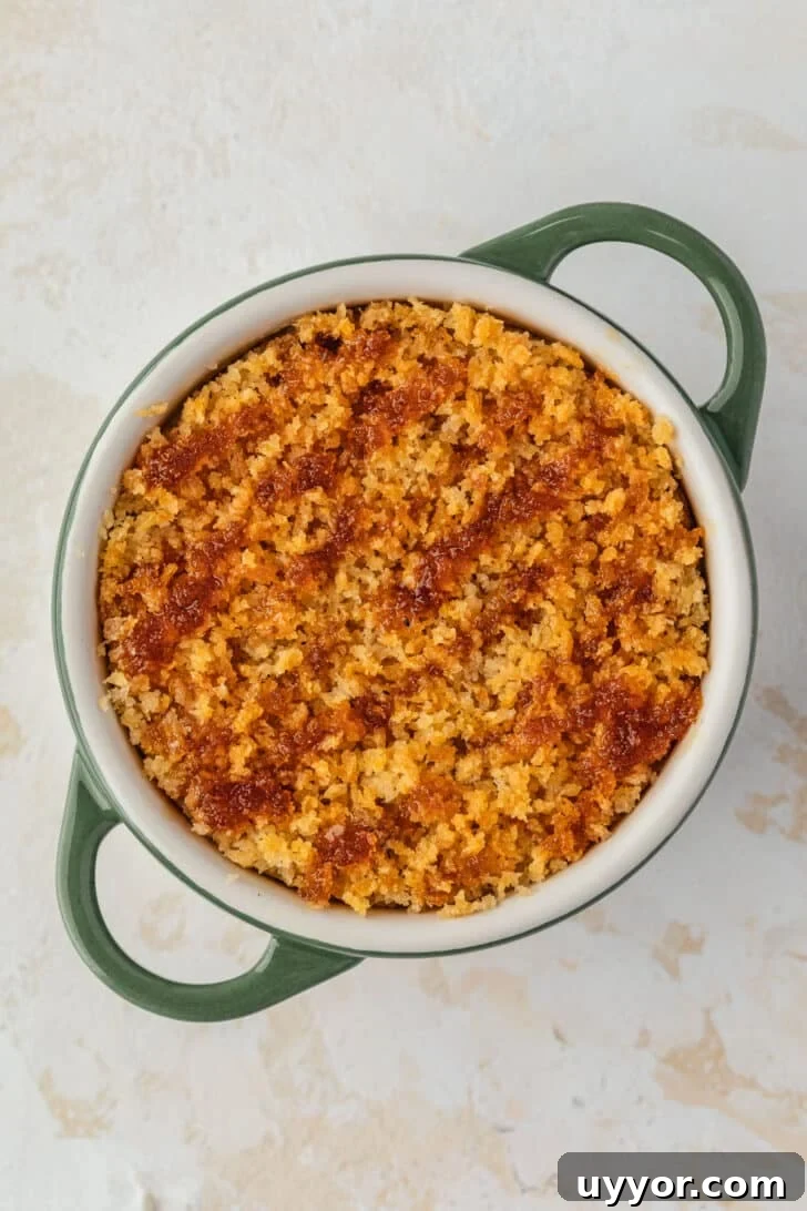 Crispy Baked Boursin Bites Without Dredging 8 A green ramekin of baked boursin cheese with hot honey on a tan counter.