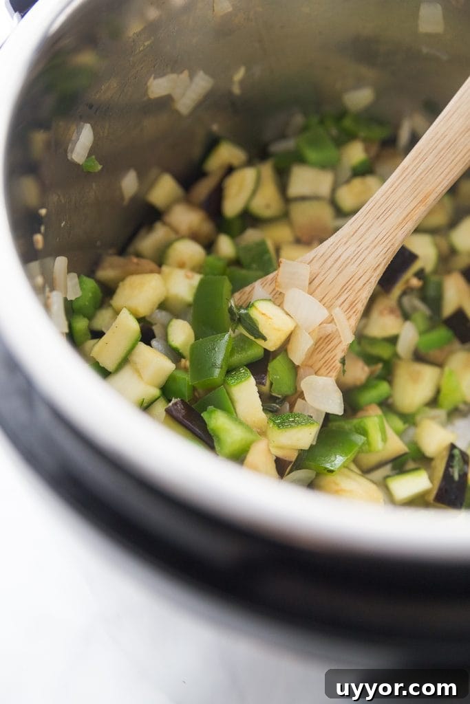 Instant Pot Ratatouille: Quick French Vegetable Stew Recipe 3 Chopped zucchini, peppers, and onions being cooked in the Instant Pot with a wooden spoon resting on the side
