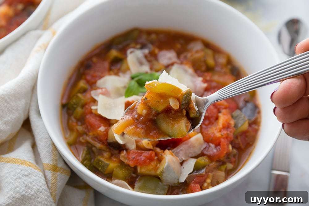 Instant Pot Ratatouille: Quick French Vegetable Stew Recipe 6 A spoonful of veggies is poised for eating- a portion of ratatouille topped with Parmesan is in a white bowl in the background.