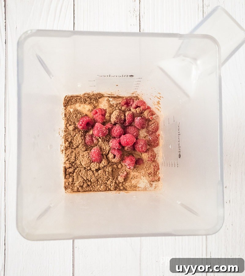 Brown dry ingredient and raspberries in a clear container.