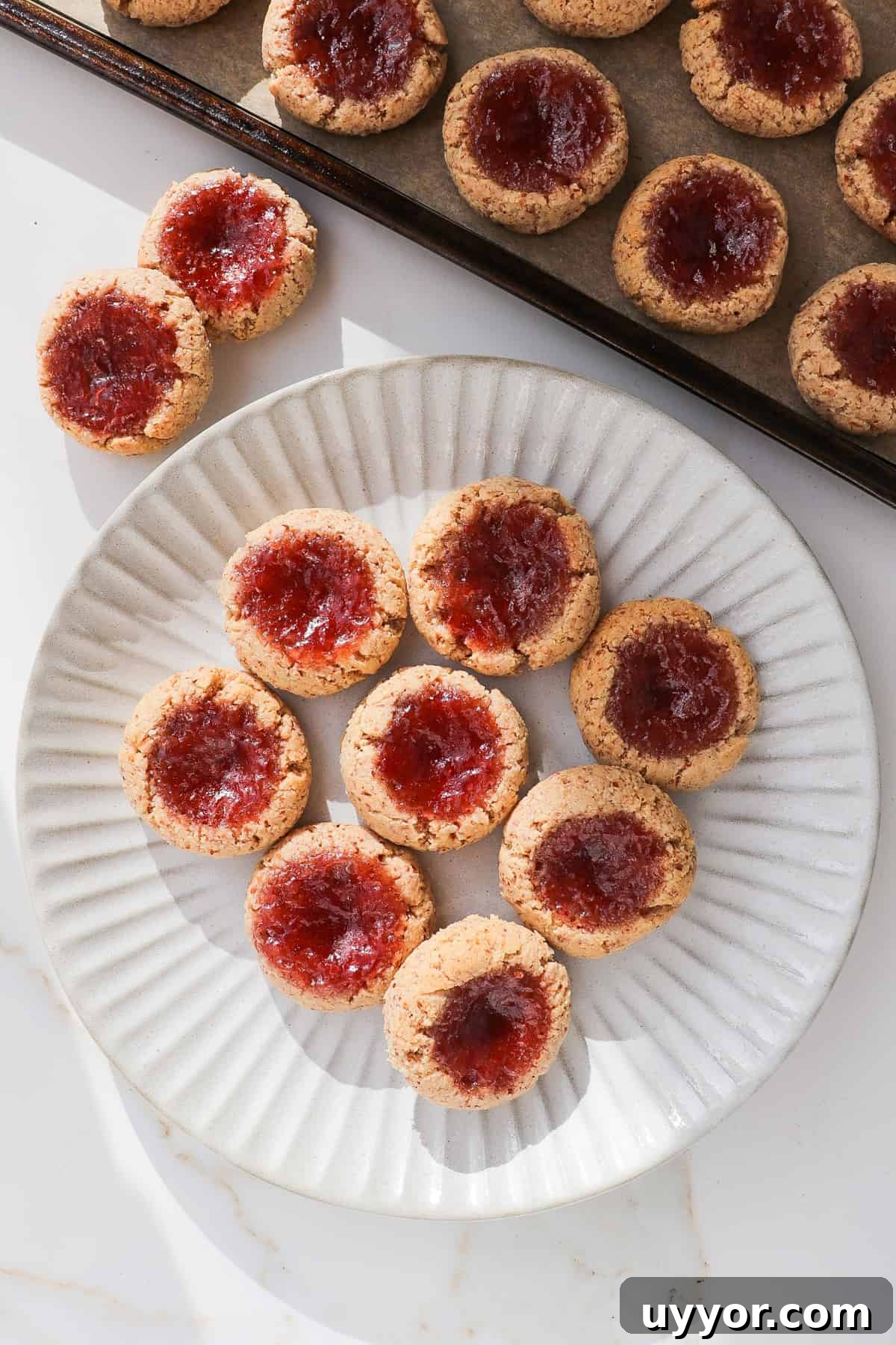Strawberry jam thumbprint cookies on a plate with tray at the top.