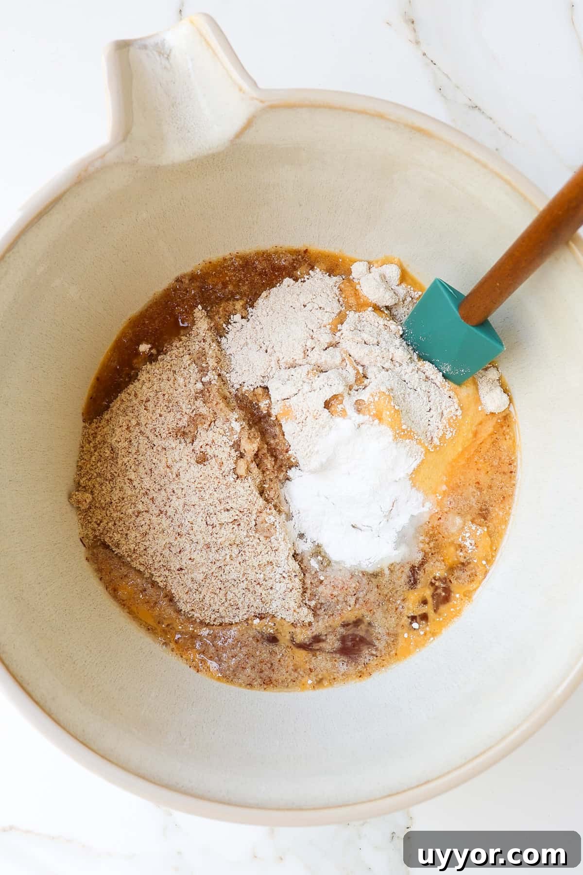 Cookie dough ingredients in a mixing bowl with a spatula.