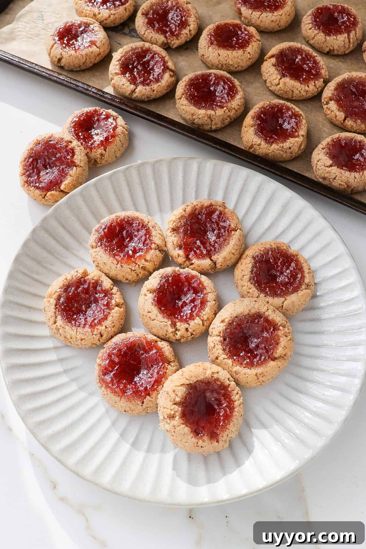 Side shot of strawberry jam thumbprint cookies on a plate.
