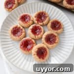 Side shot of strawberry jam thumbprint cookies on a plate.