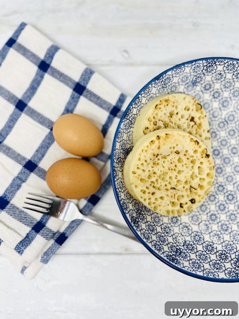 crumpets in a bowl 2 eggs on the counter top sitting on a blue and white check cloth