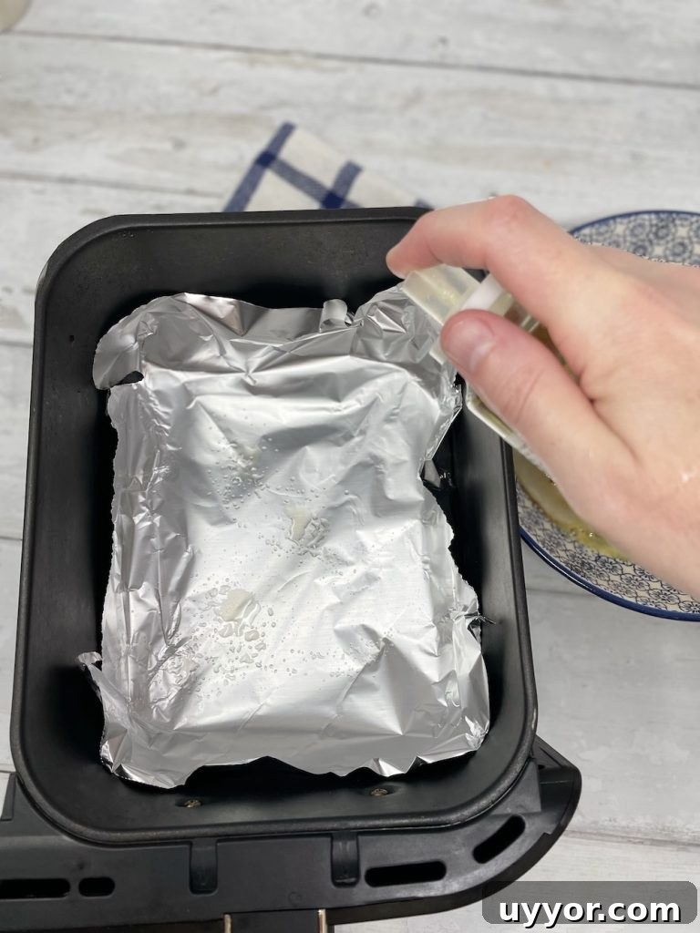 lining an air fryer basket with tin foil and spritzing with olive oil cooking spray