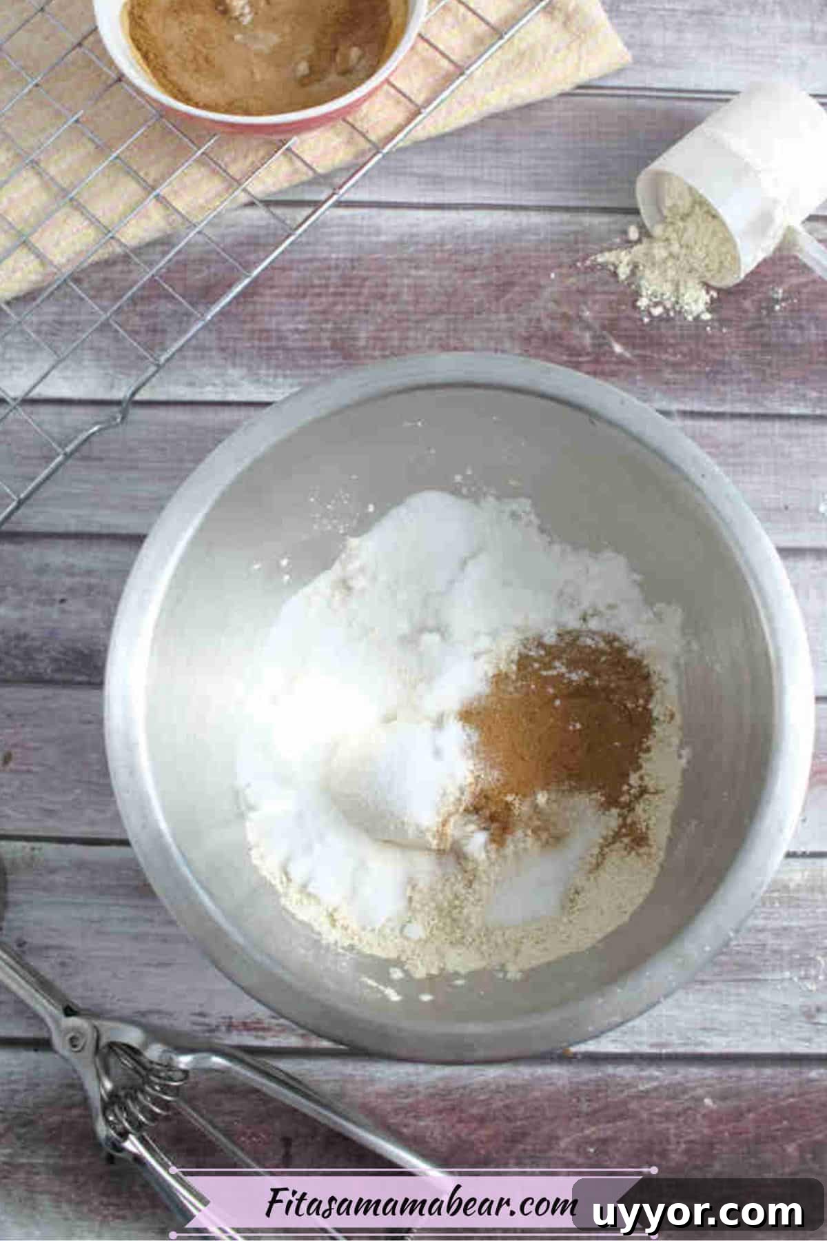 Steel bowl with flour and protein powder in it and a cooling rack, and more protein behind it.