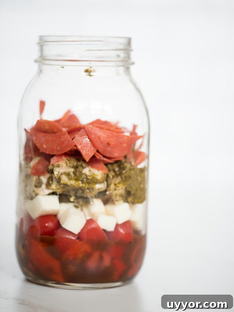 Pesto Chicken Mason Jar Salad Recipe for Meal Prep 9 balsamic vinaigrette, roasted peppers, grape tomatoes, basil pesto chicken, pepperoni, and mozzarella in a jar