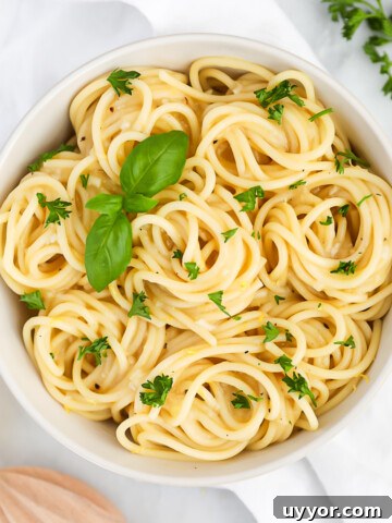 A white bowl filled with pasta covered in a lemon sauce.