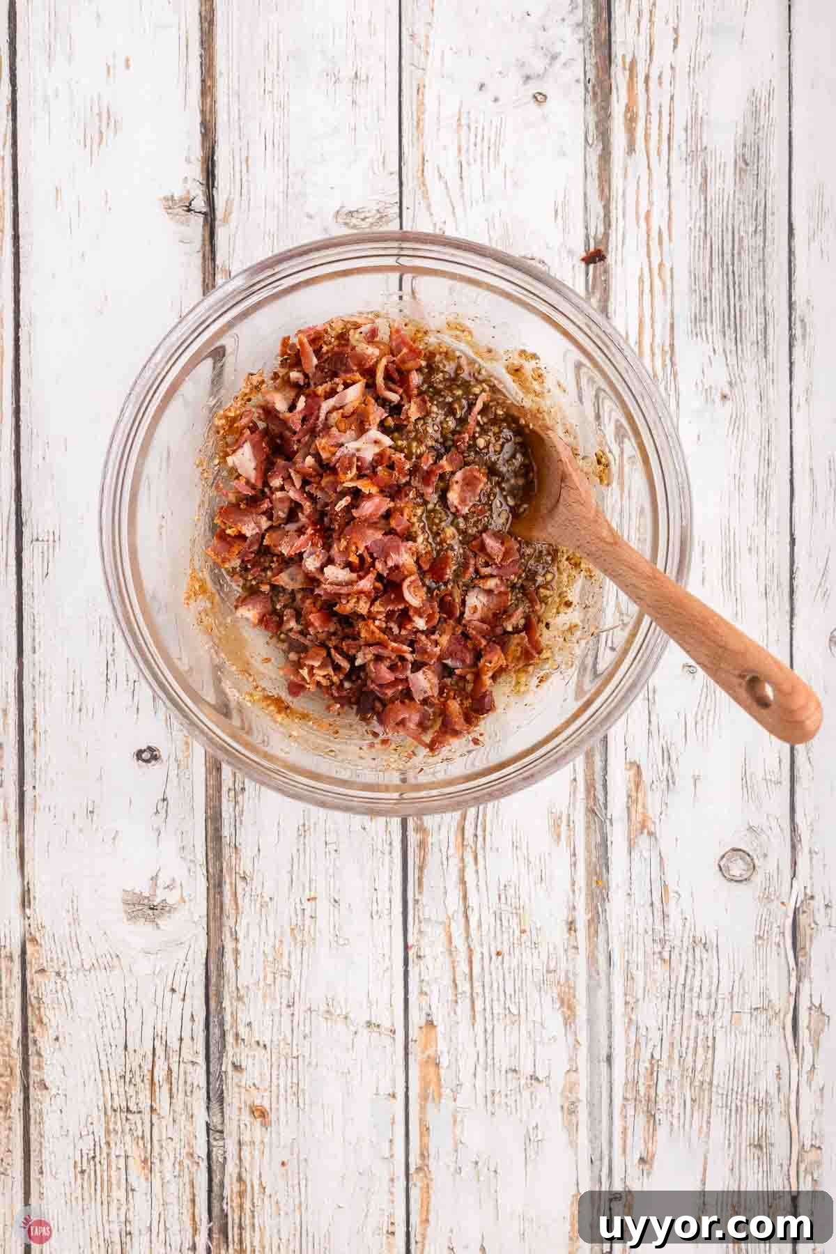 clear bowl with bacon jam and a wood spoon