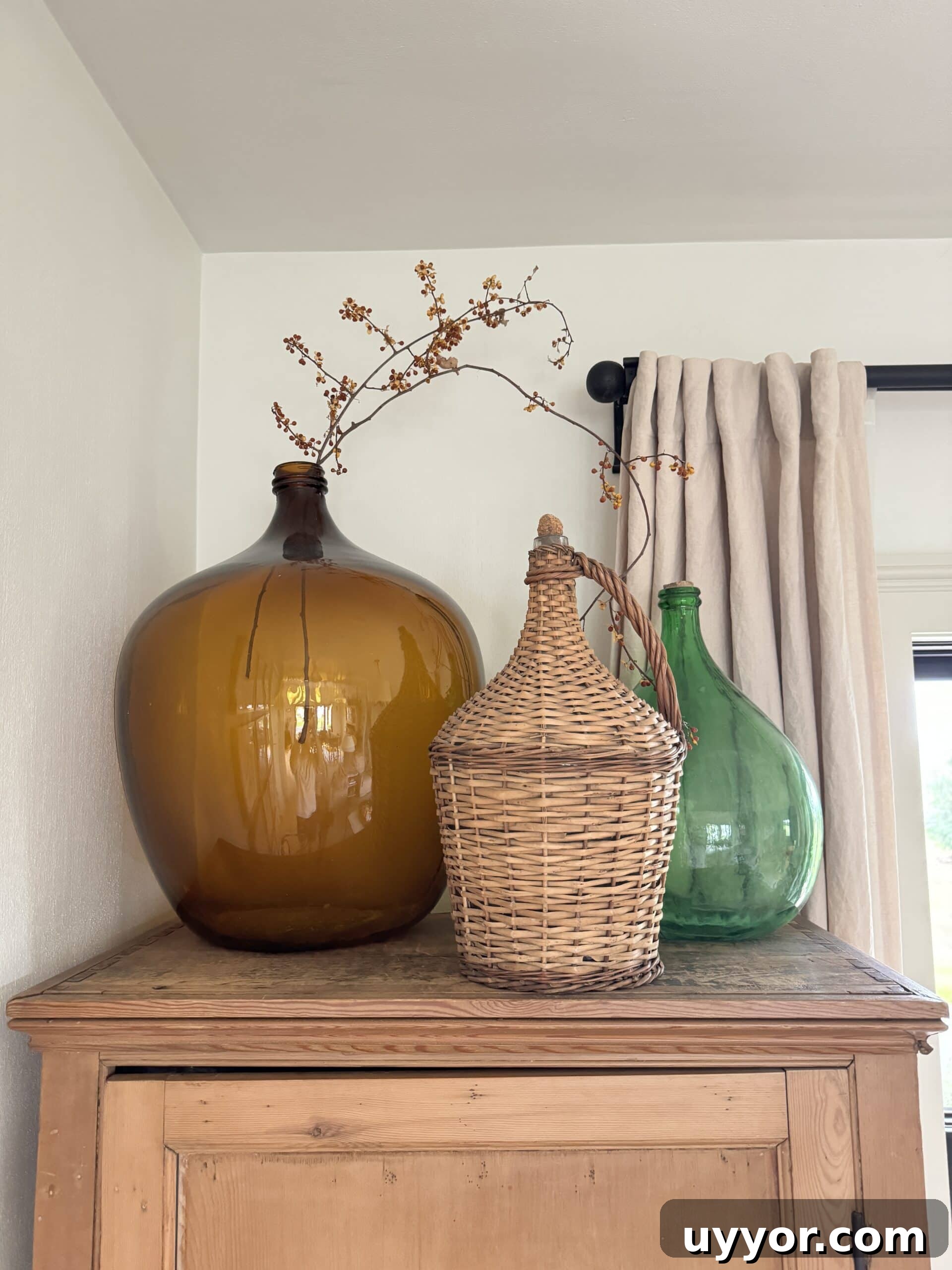 August 2024 Events, Deals & Planning Guide 4 Pine cabinet in living room with large glass vessels on top one with sprig of bittersweet.