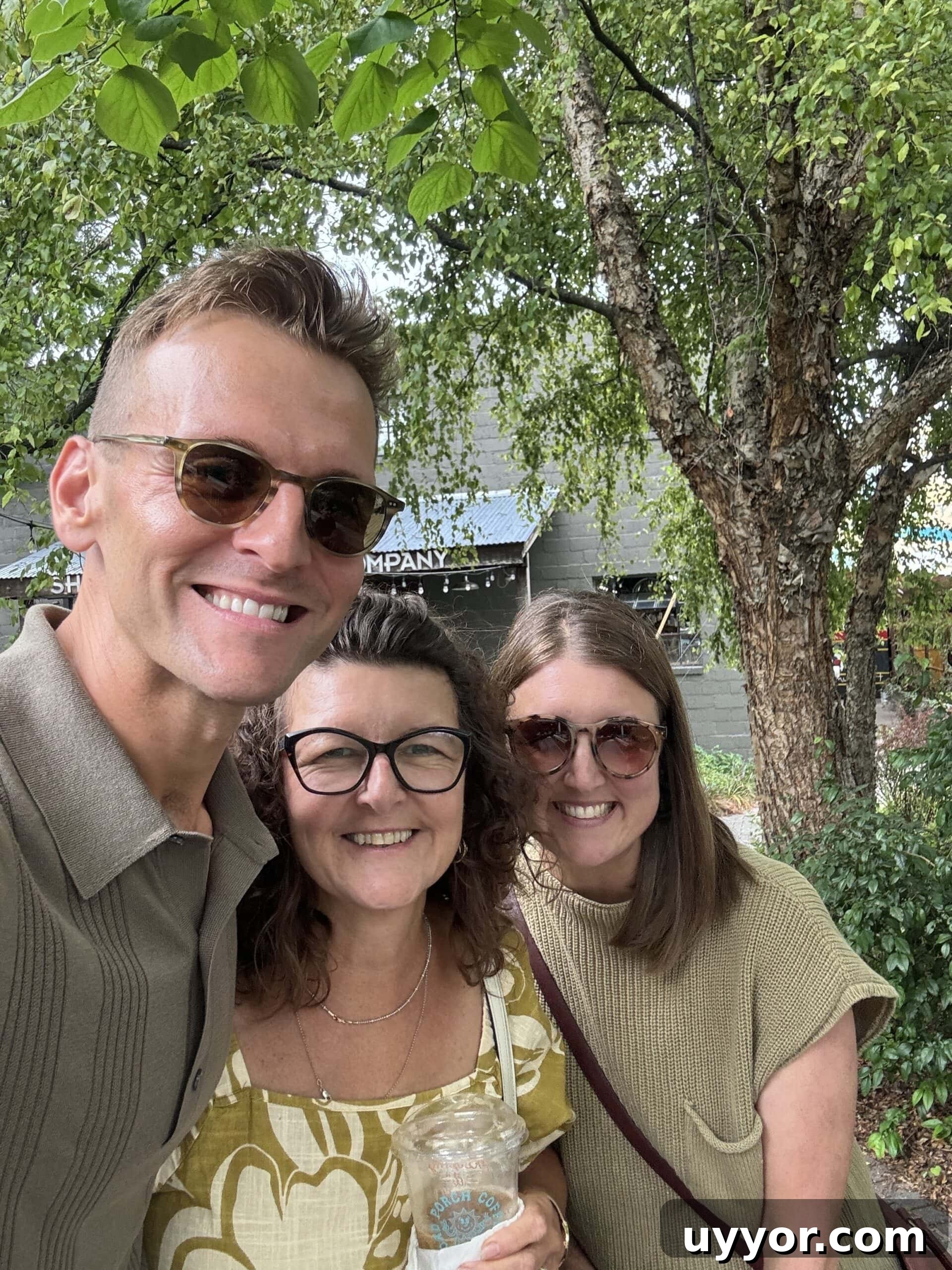 August 2024 Events, Deals & Planning Guide 9 Kaleb Wyse wearing sunglasses standing in a group hug with his mom and sister while on a trip.