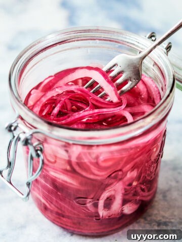 Quick pickled onions in a glass jar with a fork.