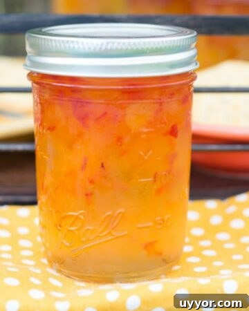 A canning jar filled with Habanero Apricot Jelly on a yellow cloth napkin.