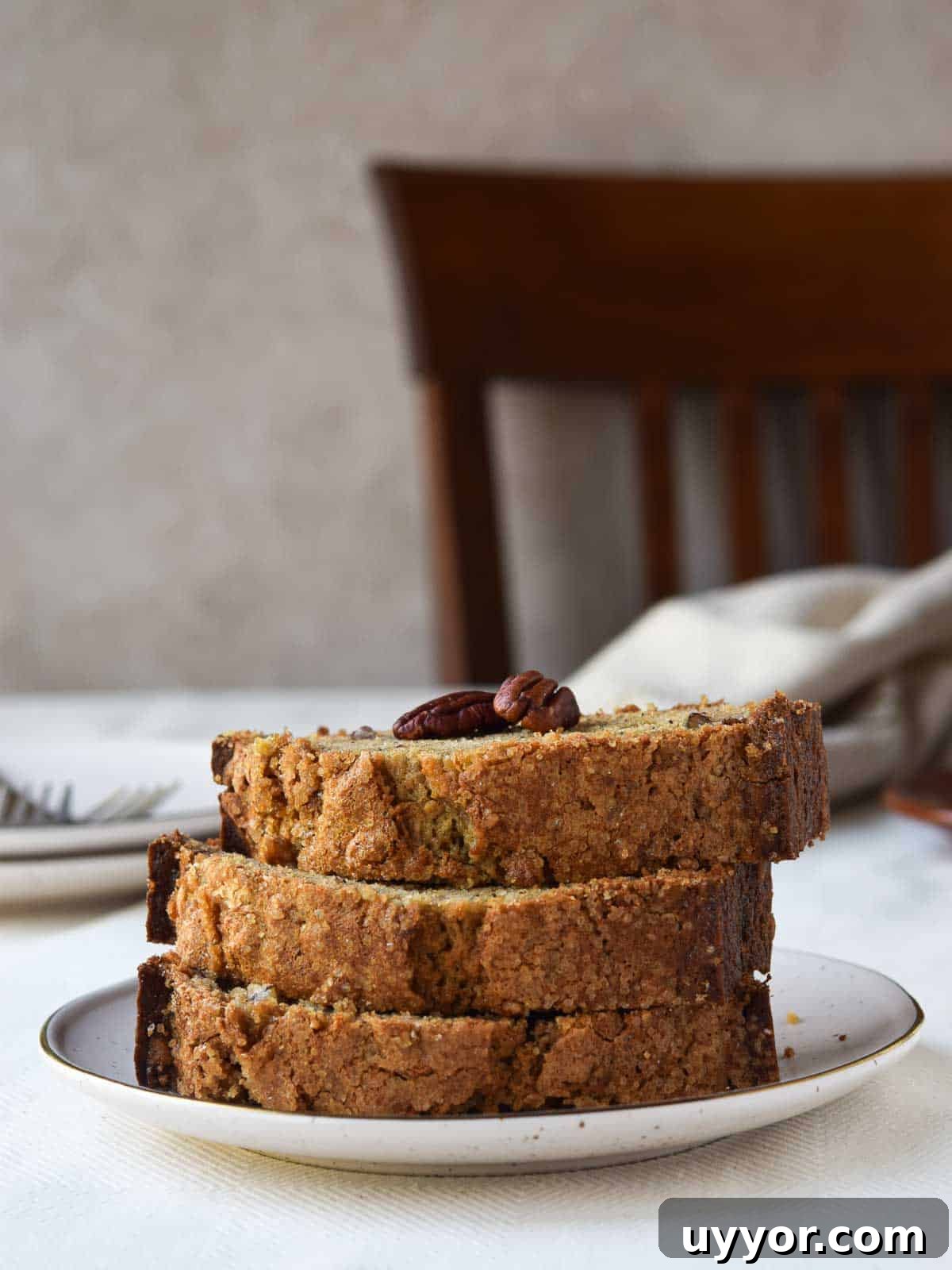 Bakery-Style Banana Bread with Pecans and Brown Butter Glaze 11 Close-up of banana bread cut and stacked tall on a plate.