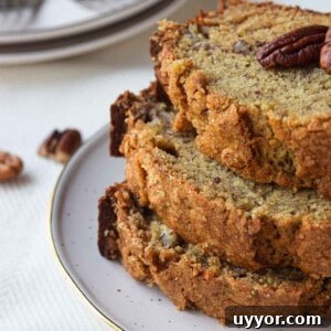 Bakery-Style Banana Bread with Pecans and Brown Butter Glaze 12 Three slices of banana bread stacked on a beige plate.