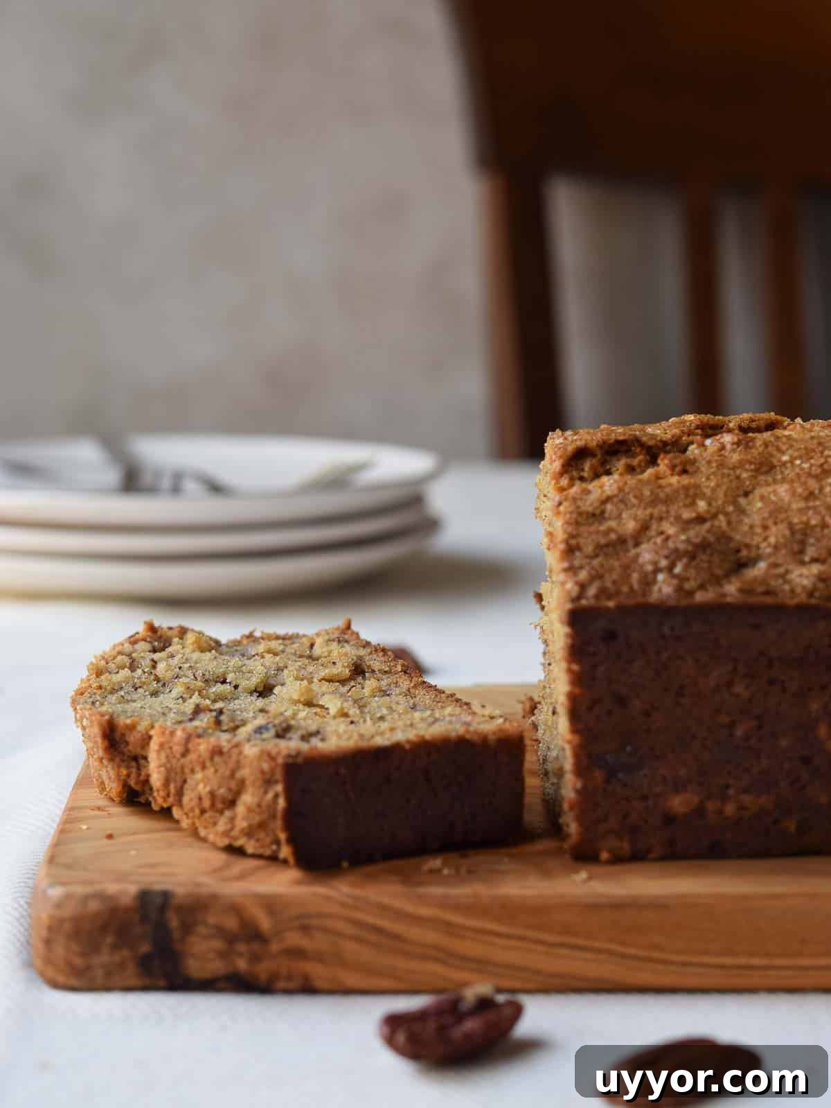 Bakery-Style Banana Bread with Pecans and Brown Butter Glaze 10 A slice of banana bread cut from a loaf on a kitchen table.