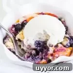 Perfect Blueberry Peach Cobbler Recipe for Summer Desserts 6 fork digging into a bowl of cobbler with vanilla ice cream on top