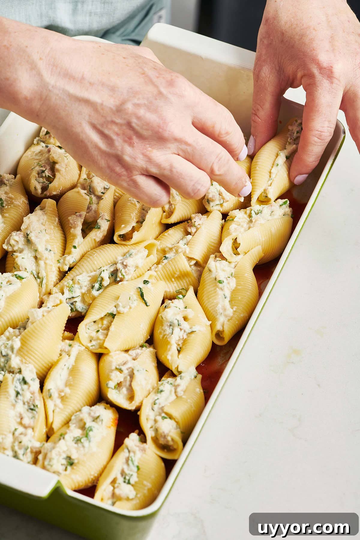 Top Baked Pasta Recipes for Comforting Weeknight Dinners 4 Woman arranged stuffed pasta shells in a baking dish.