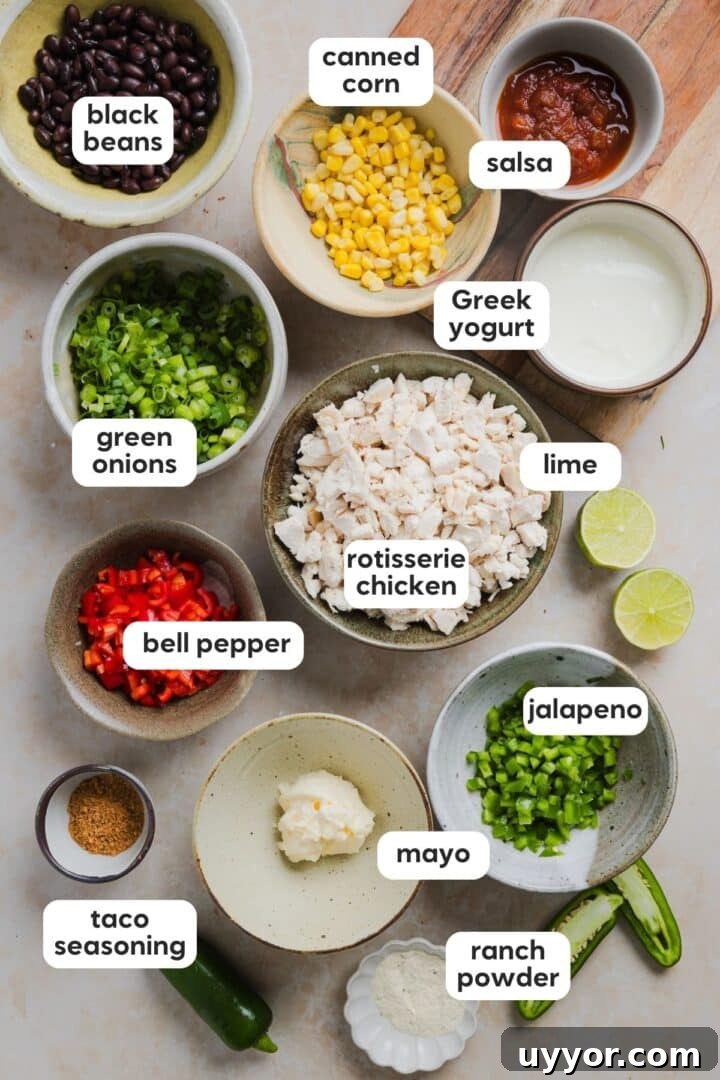 Labeled photo of ingredients for southwest chicken salad displayed in small bowls on a marble counter.