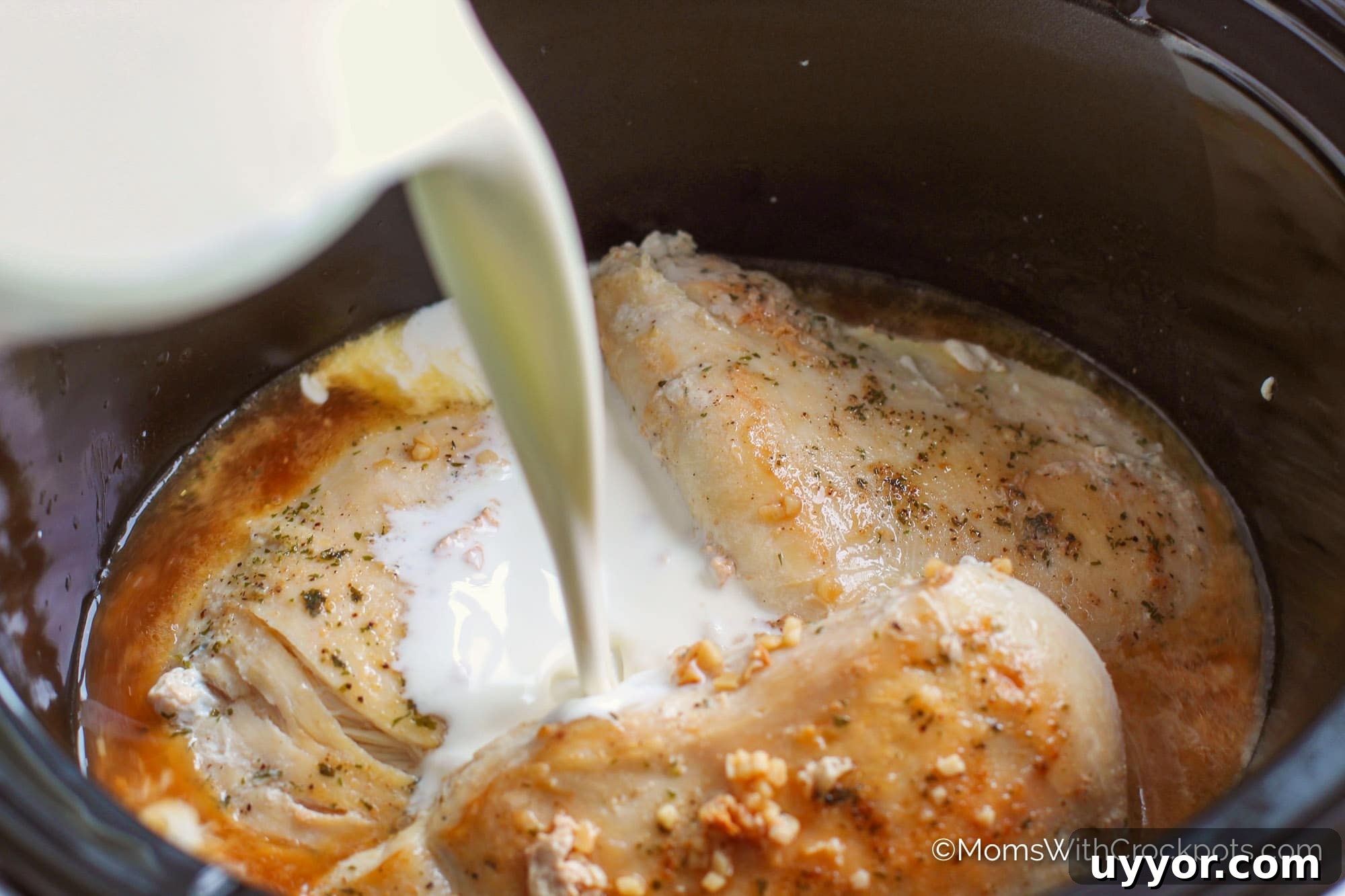 Cream being poured on chicken in slow cooker