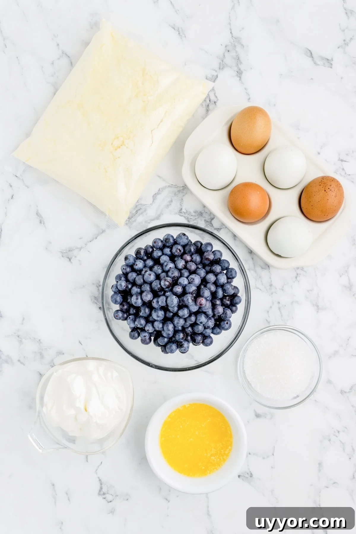 Blueberry Muffins from Cake Mix: Quick Homemade Recipe 3 Fresh blueberries, eggs, flour, sugar, butter, and cream on a marble countertop for baking.