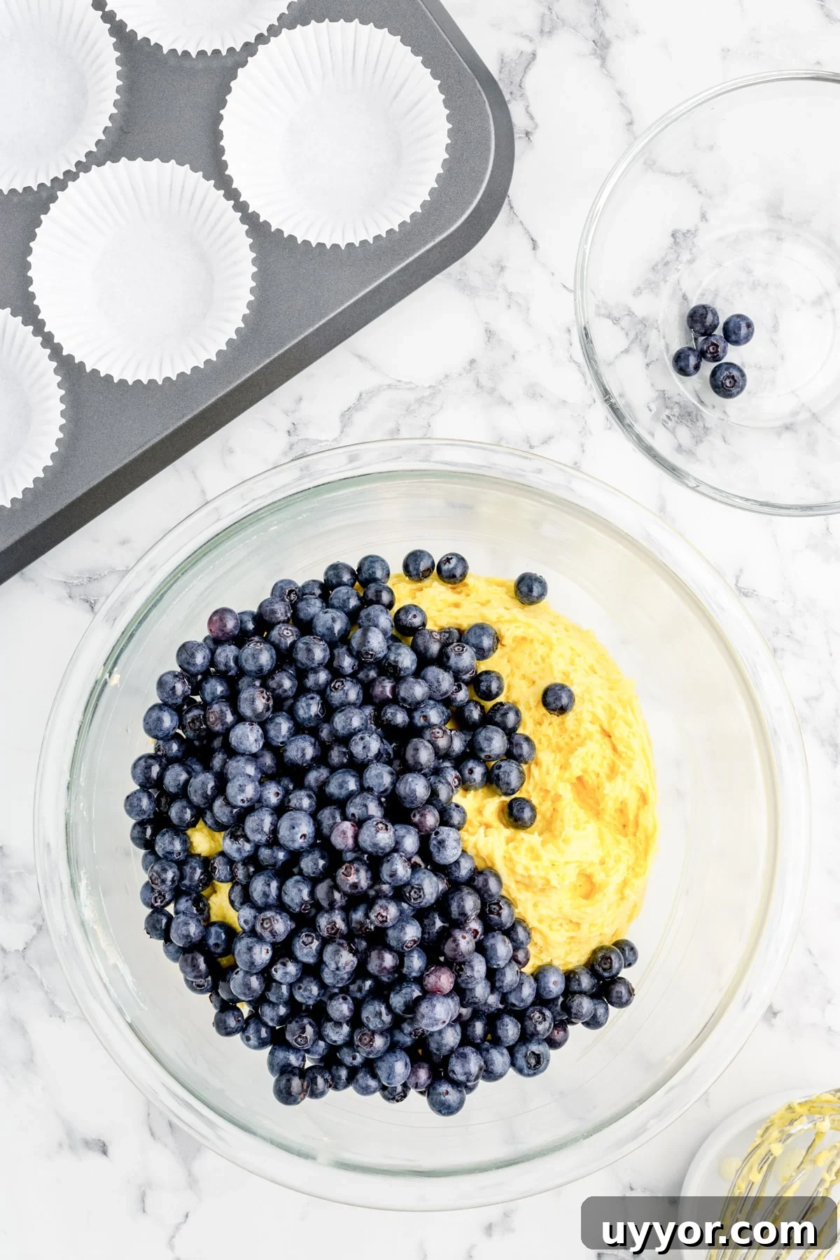 Blueberry Muffins from Cake Mix: Quick Homemade Recipe 6 Folding fresh blueberries into the muffin batter that is in a mixing bowl.